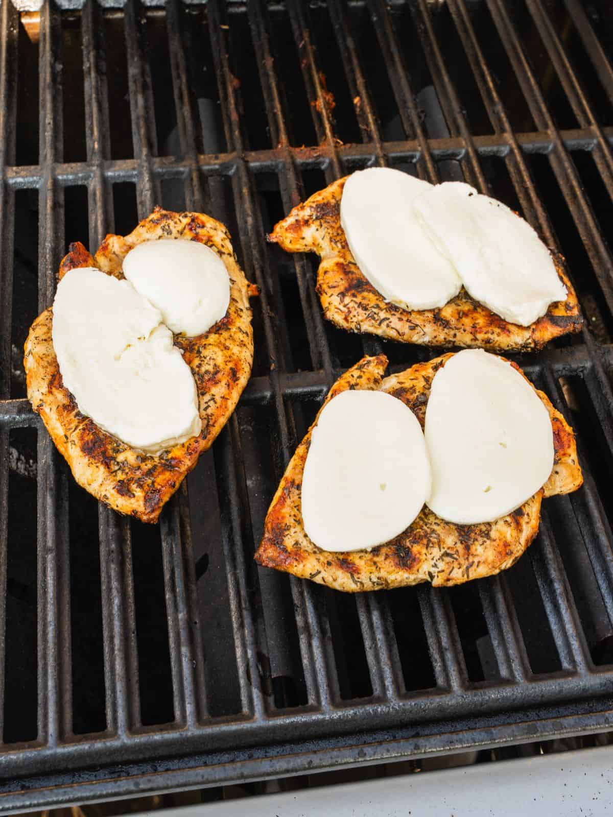Cheese slices added to the grilled chicken on the barbecue.