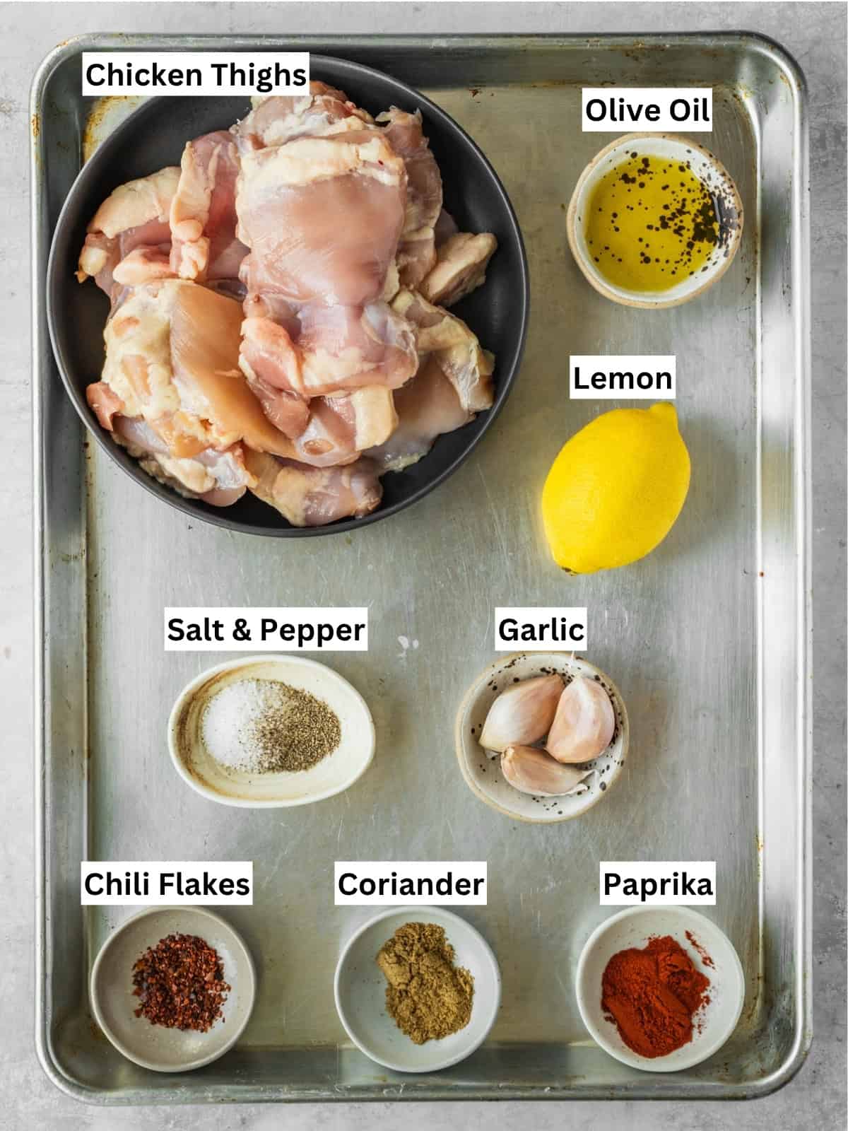 Grilled piri piri chicken thighs recipe ingredients with individual labels on a metal tray.