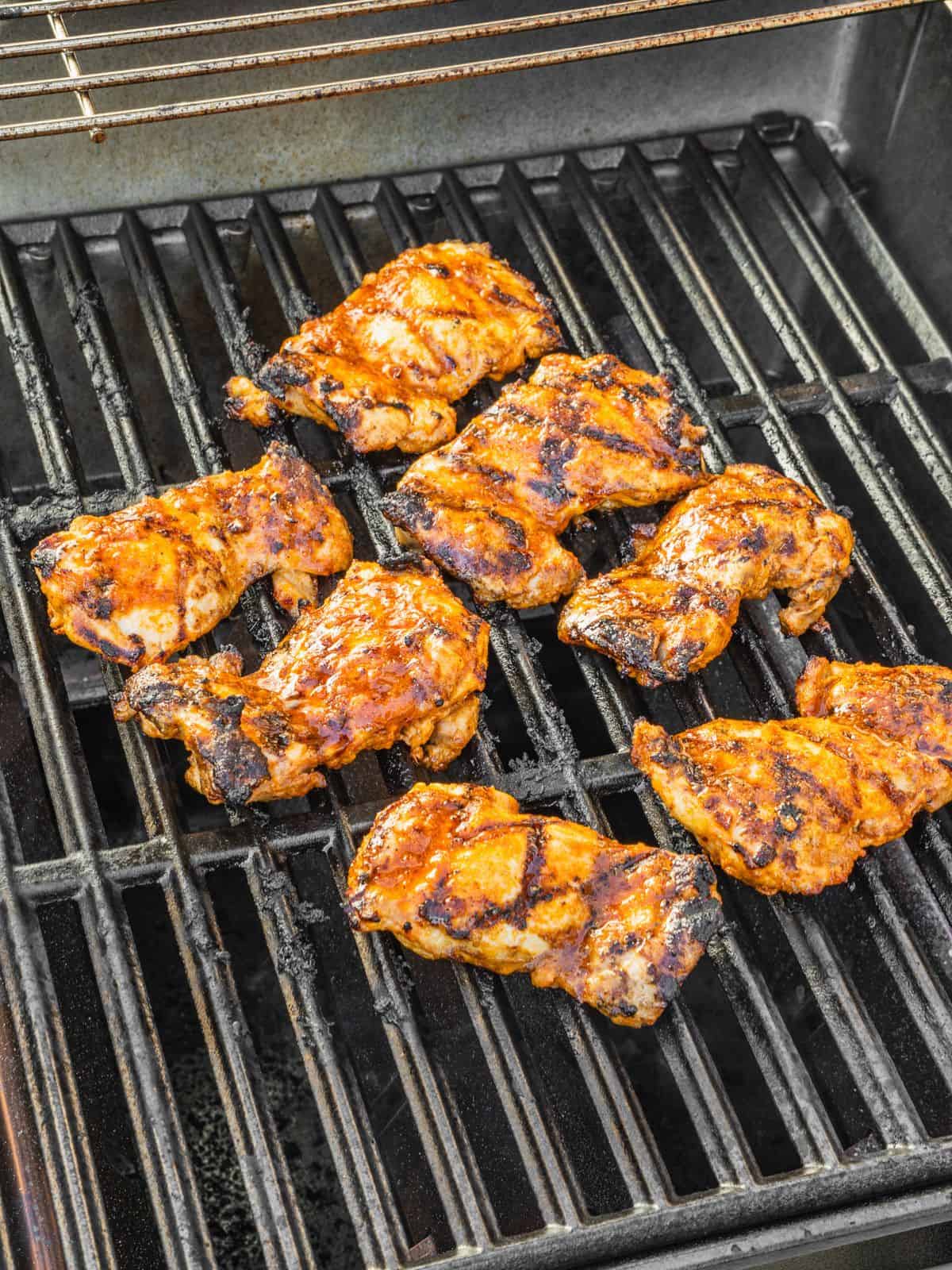 Marinated chicken thighs grilling on a gas bbq.