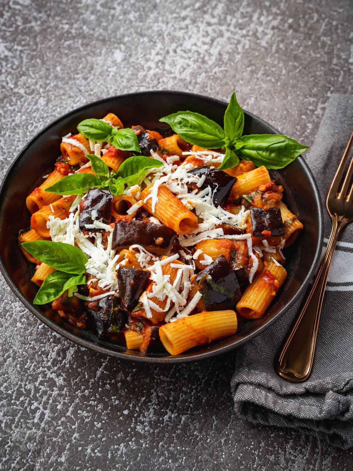 Pasta alla Norma with eggplant, basil and ricotta in a bowl.