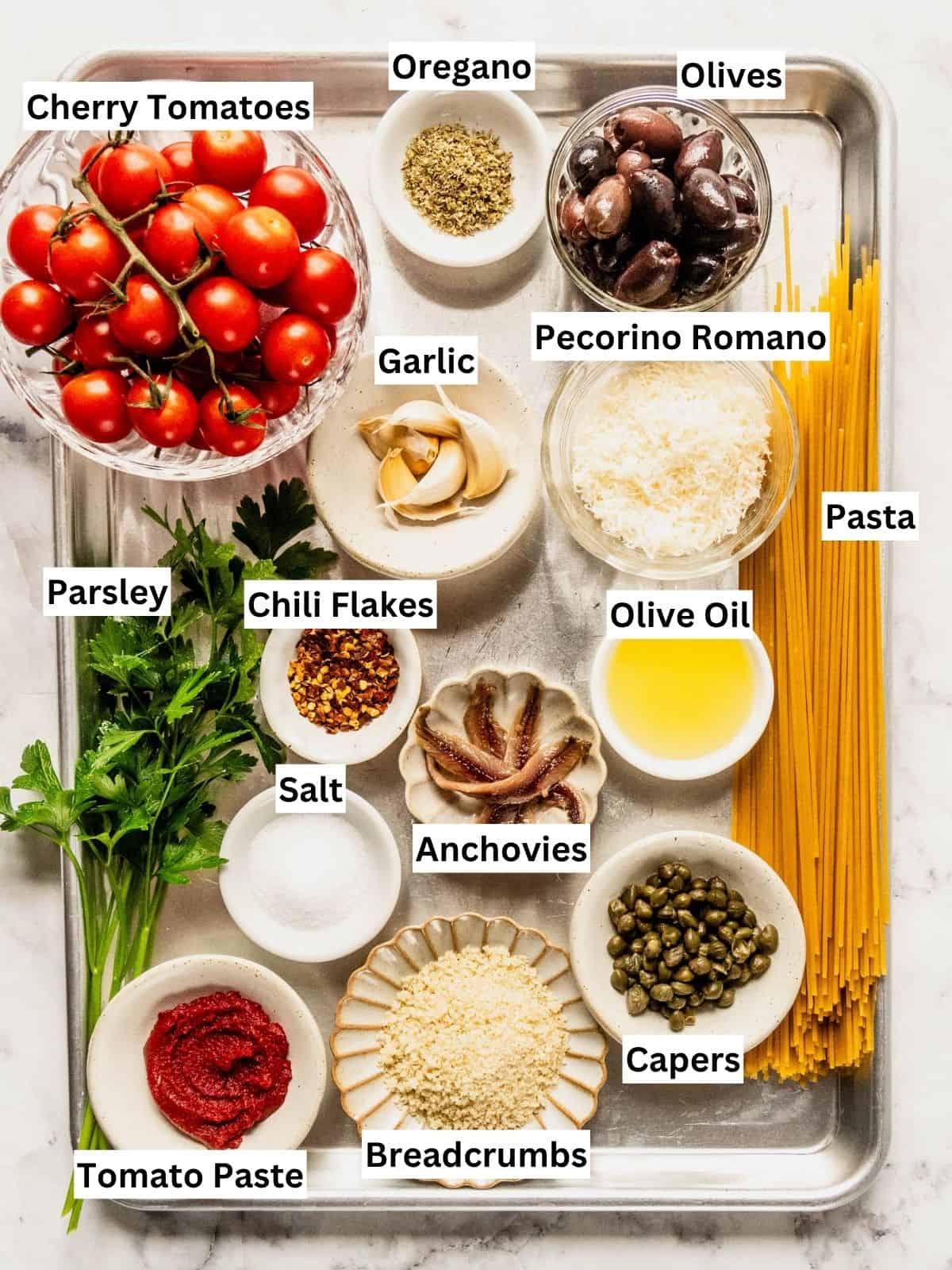 Pasta Puttanesca with cherry tomatoes recipe ingredients with individual labels on a metal tray.