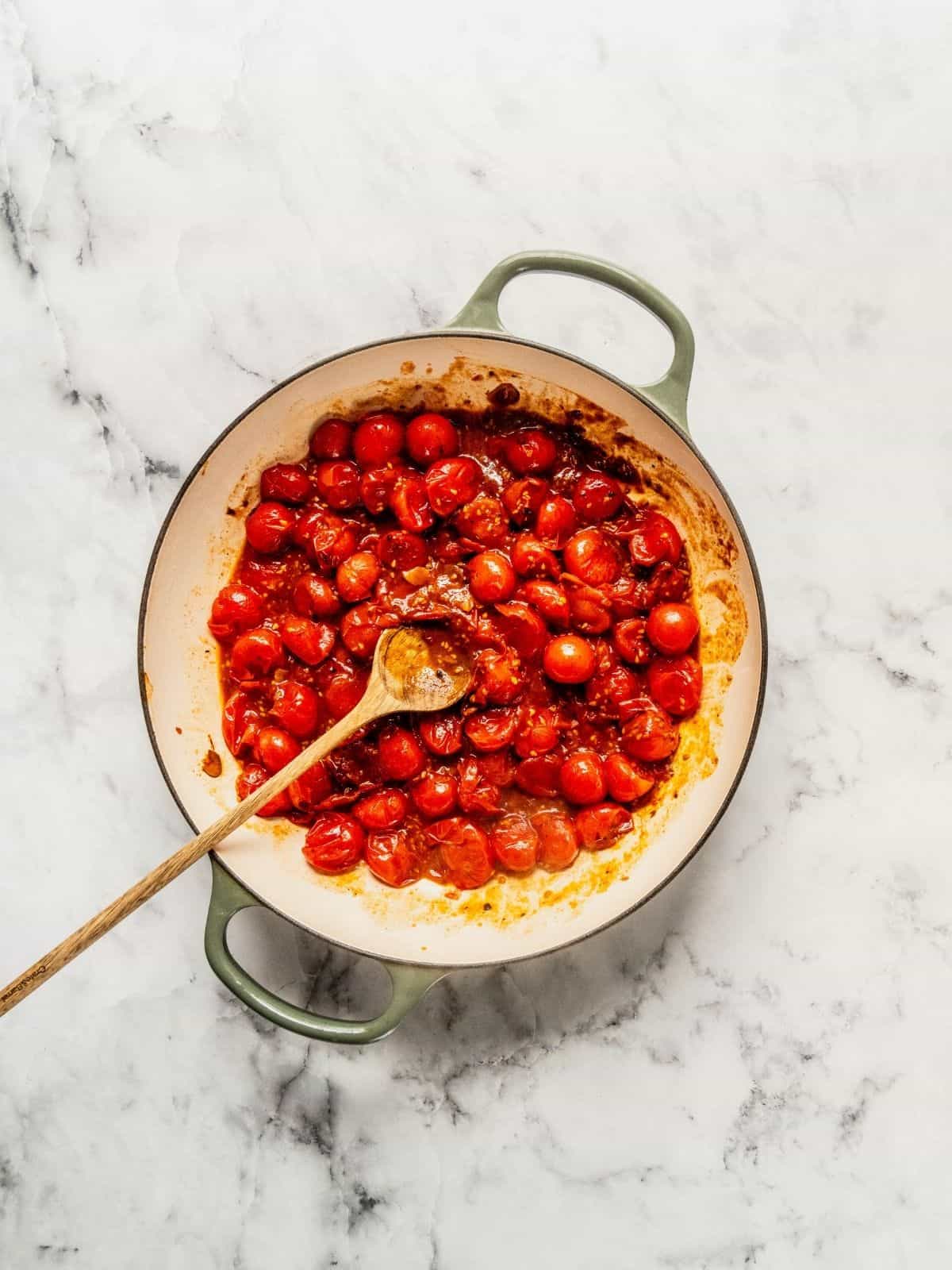 Adding the cherry tomatoes to the saucepan to build the base.