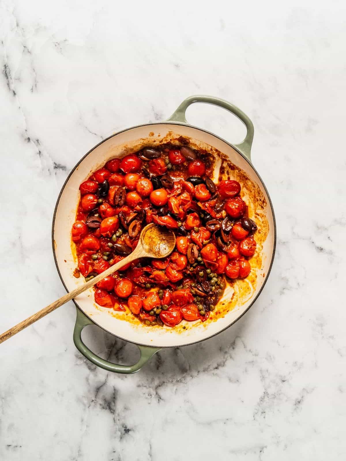 Adding the capers and olives to the sauce.