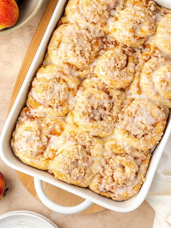 Peach cobbler cinnamon rolls in a baking dish, garnished with a simple icing.