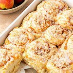 Peach cobbler cinnamon rolls in a baking dish, garnished with a simple icing.