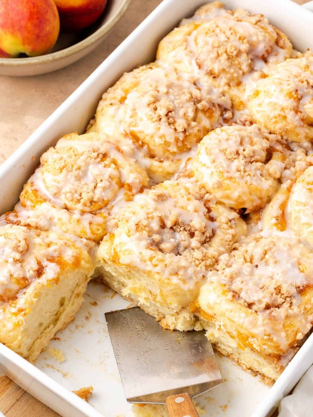 Peach cobbler cinnamon rolls in a baking dish, garnished with a simple icing.