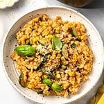 Summer risotto with squash and corn in a bowl garnished with fresh basil leaves.