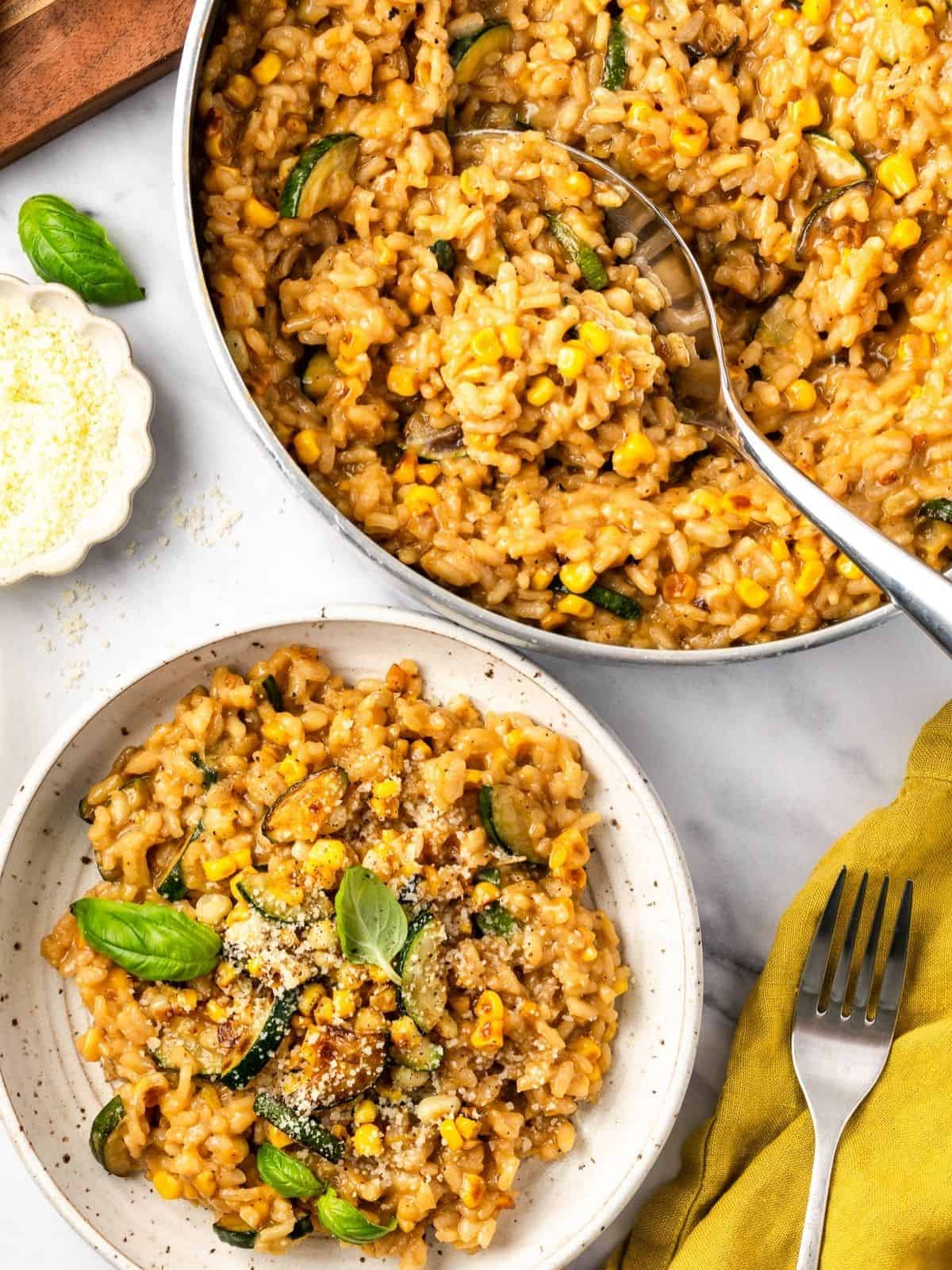Summer risotto with squash and corn in a bowl garnished with fresh basil leaves.
