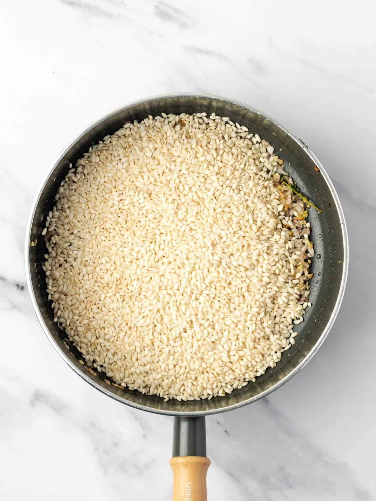Recipe step showing the rice being added to the sauteed aromatics.