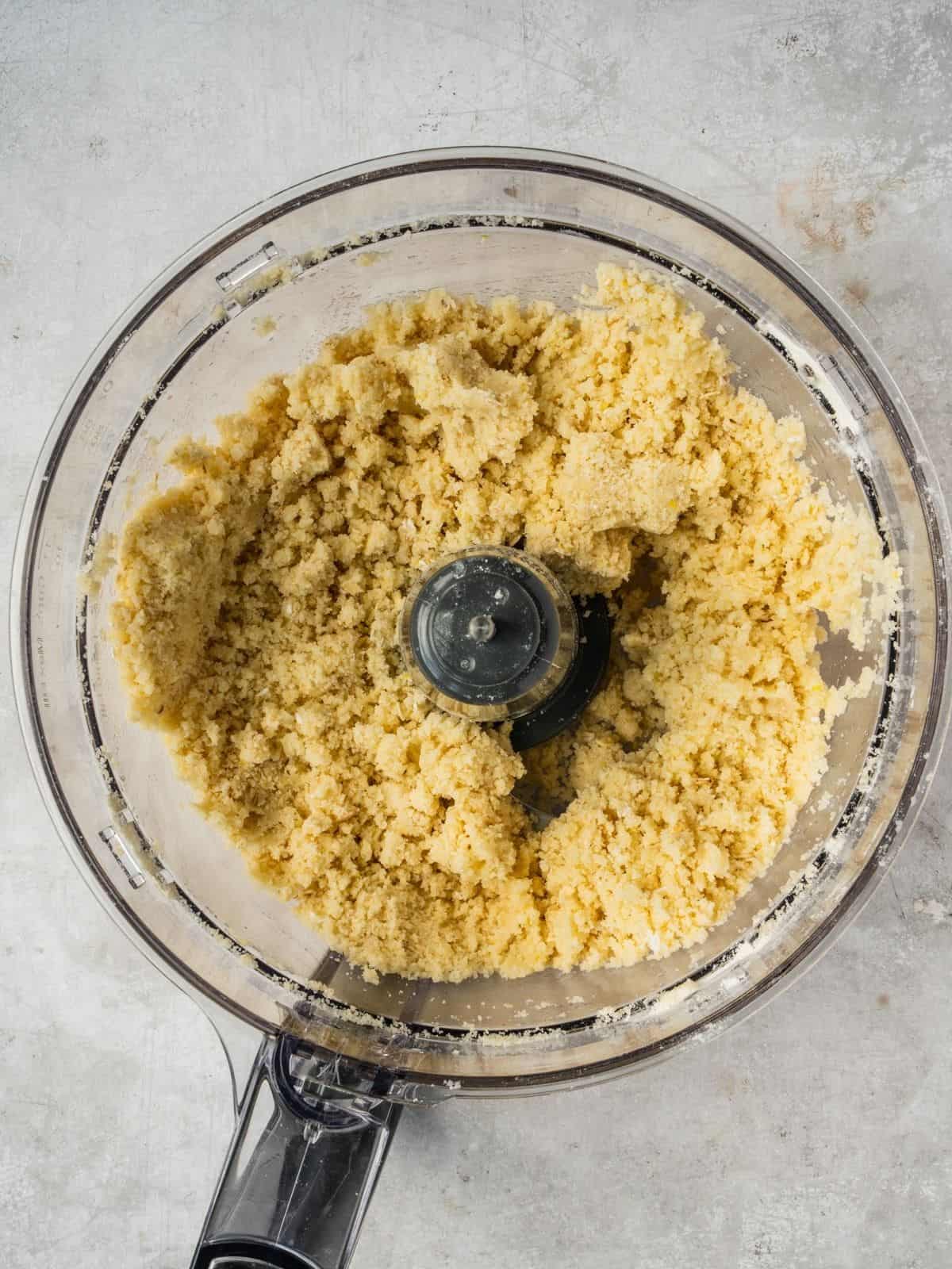 The shortcrust mixture after pulsing in a food processor bowl.