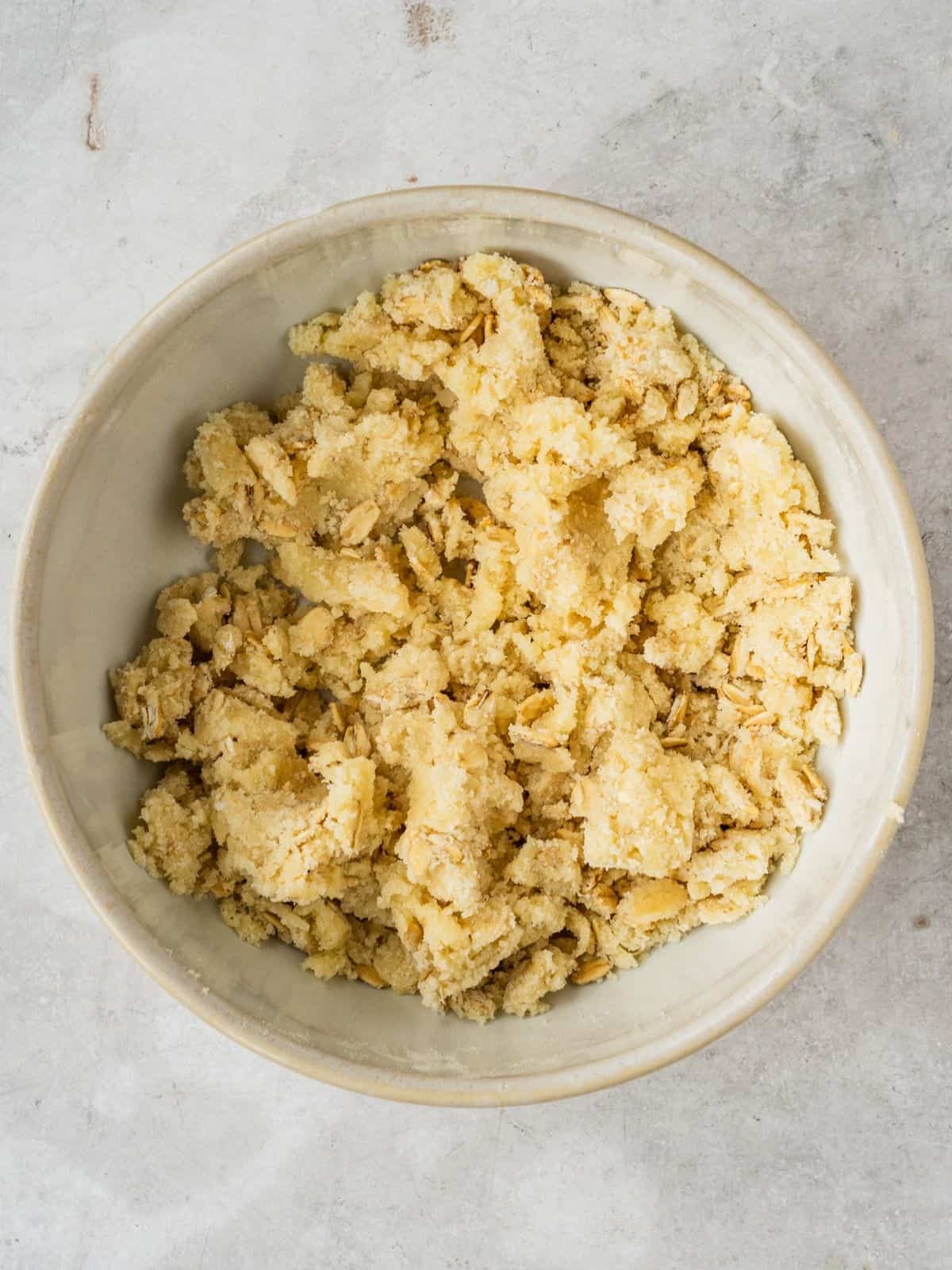Small bowl with oatmeal, flour, butter and sugar crumbs to be used as topping.