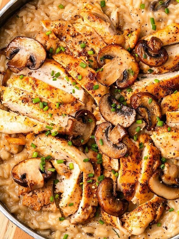 Chicken and mushroom risotto in a sauté pan garnished with fresh chives.