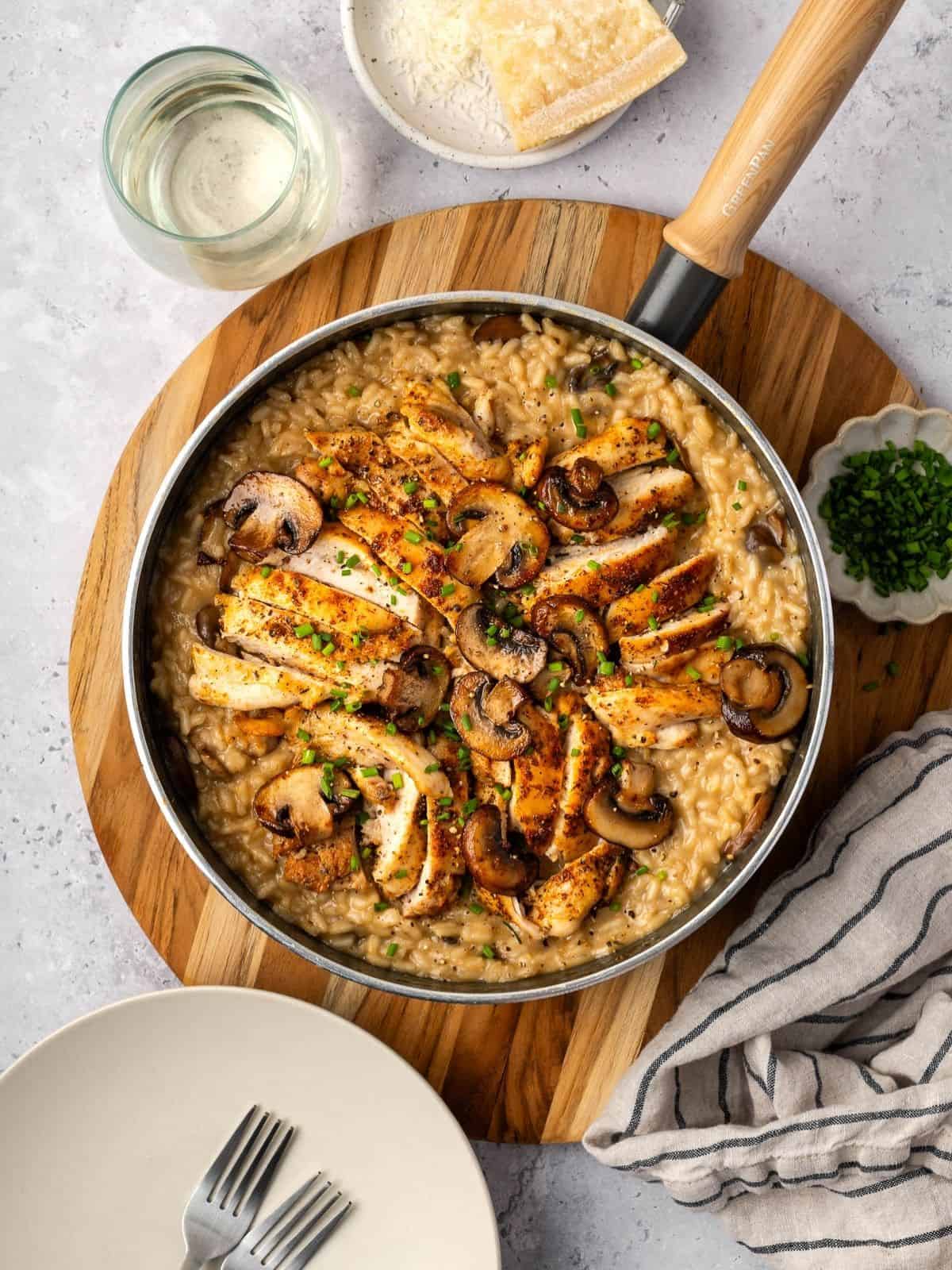 Chicken and mushroom risotto in a sauté pan garnished with fresh chives.