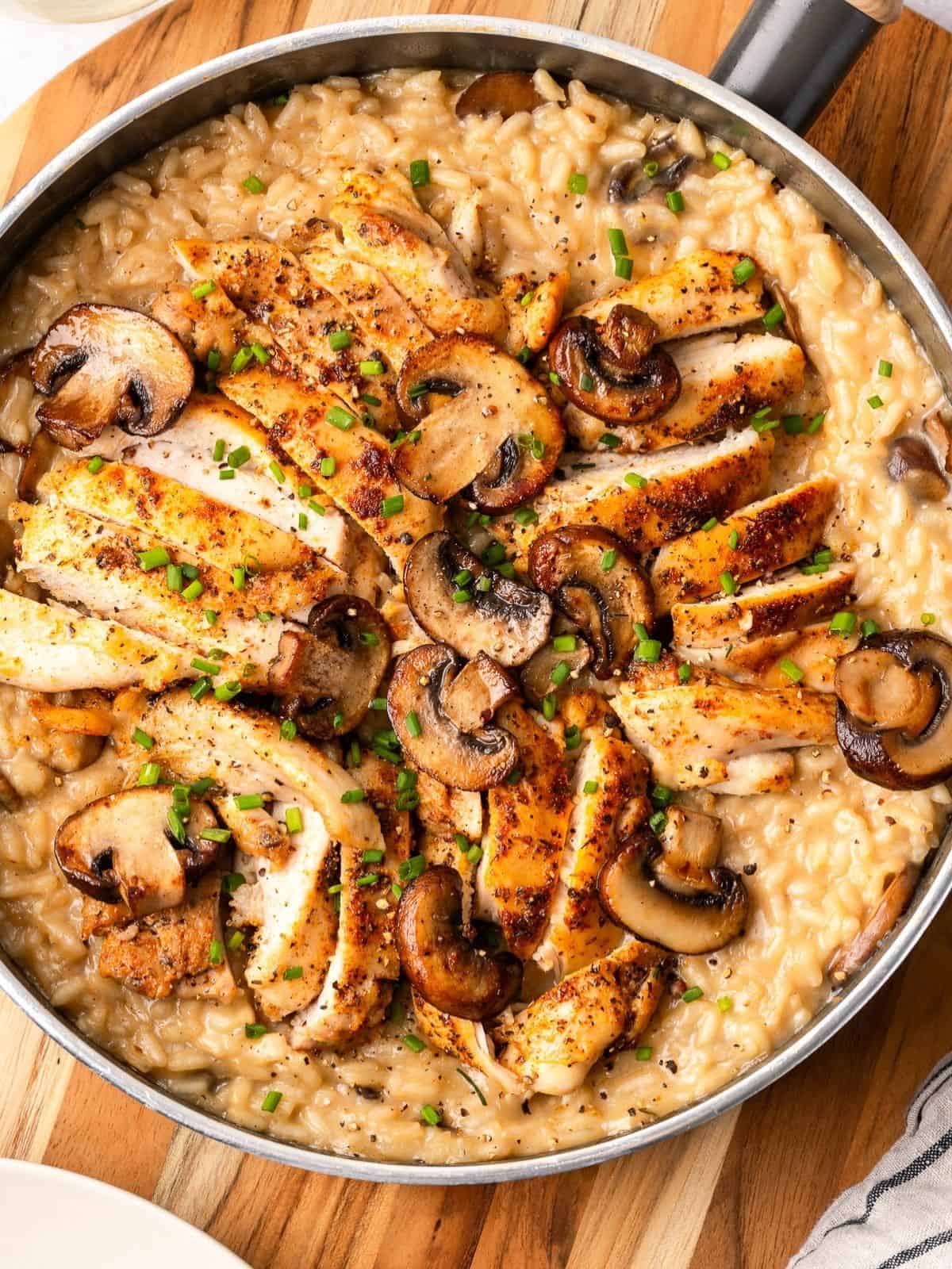Chicken and mushroom risotto in a sauté pan garnished with fresh chives.
