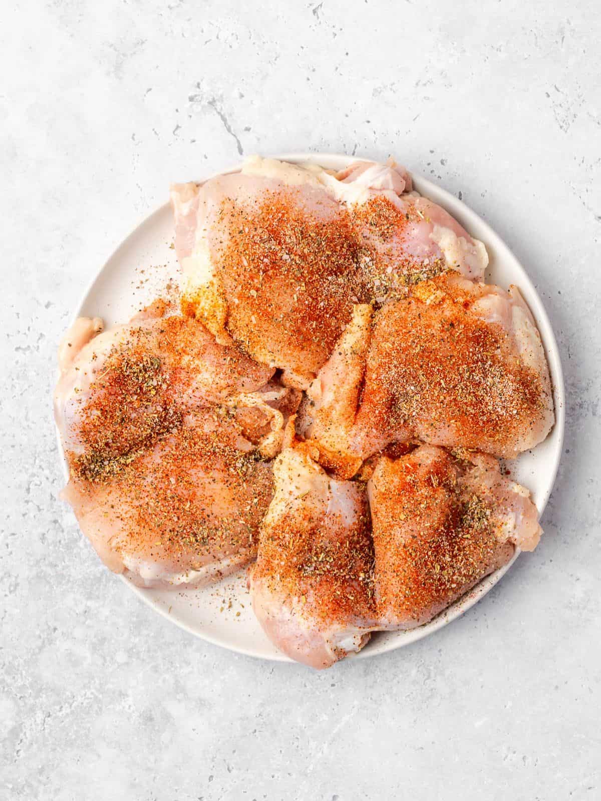 Chicken thighs seasoned with spices on a plate.