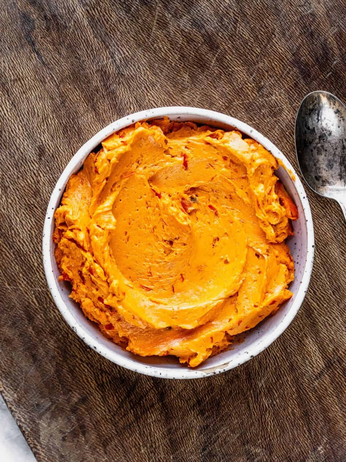 Bowl of harissa butter on a wooden tray.
