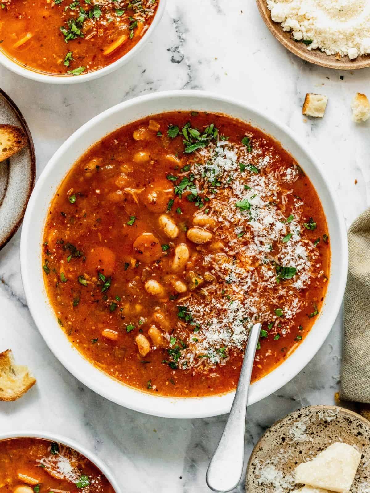 A bowl of fasolada Greek white bean soup garnished with parsley and cheese.