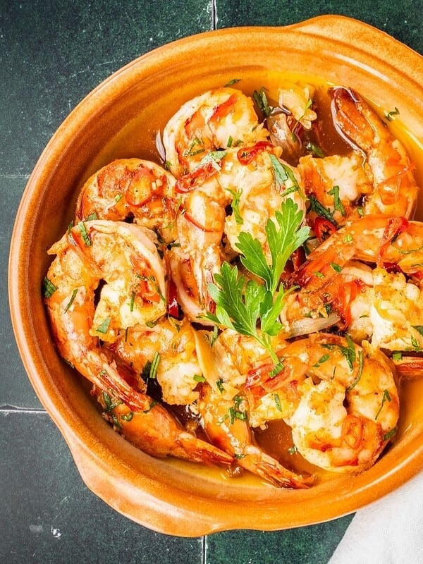 Gambas al ajillo, Spanish garlic shrimp, garnished with fresh parsley in a serving dish.