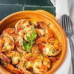 Gambas al ajillo, Spanish garlic shrimp, garnished with fresh parsley in a serving dish.