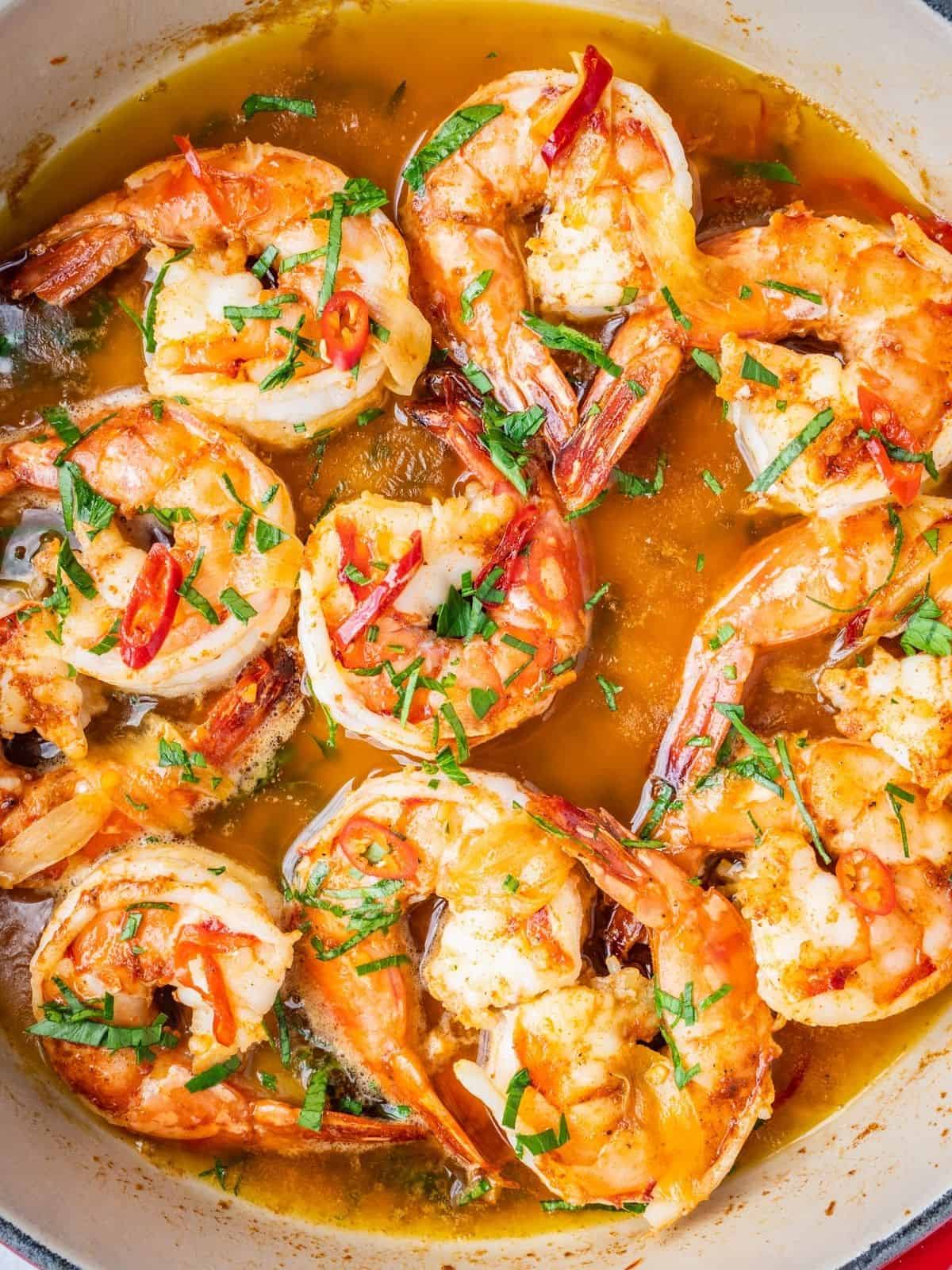 Gambas al ajillo in a skillet garnished with fresh parsley.