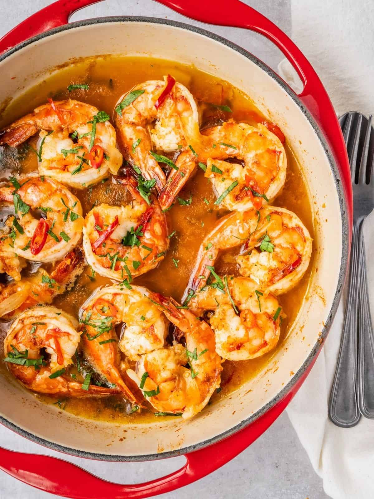 Gambas al ajillo in a skillet garnished with fresh parsley.