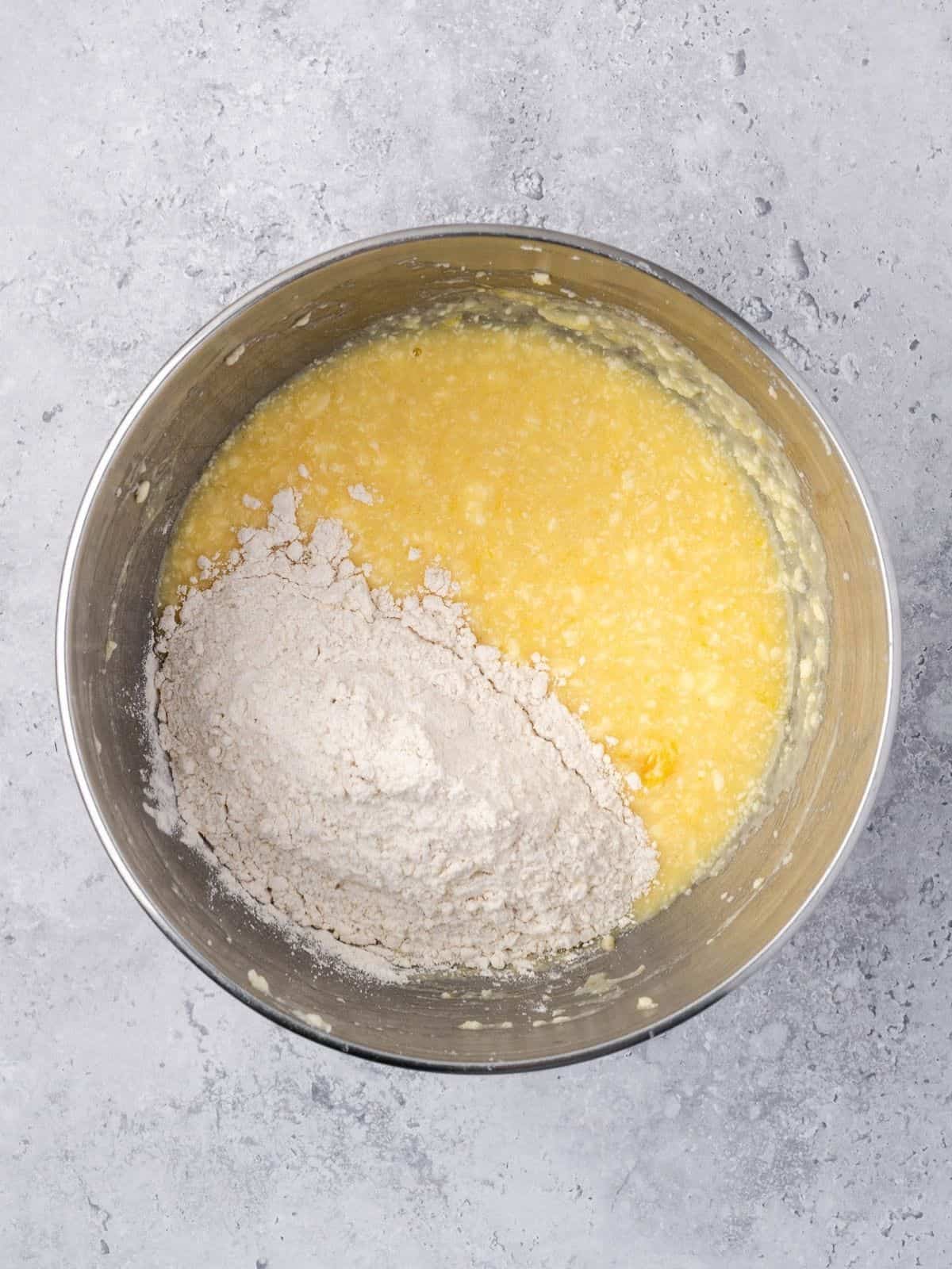Recipe step showing the addition of the dry ingredients to the wet cake batter.