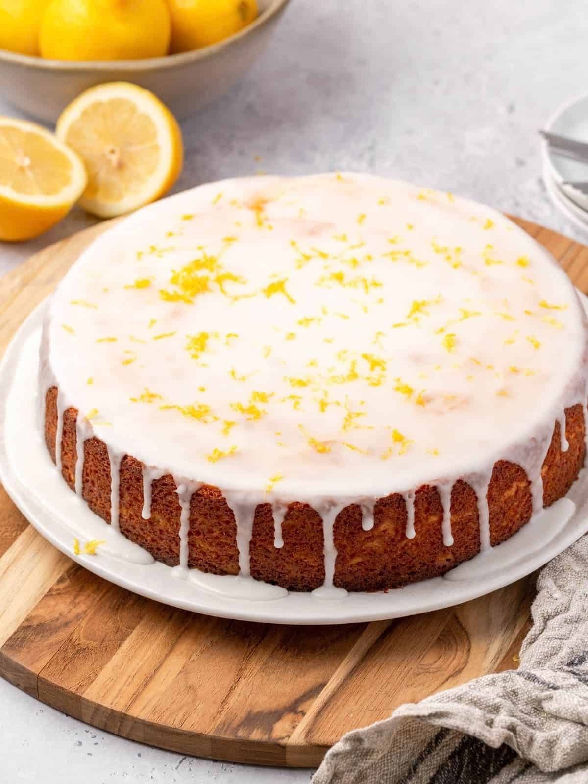 Lemon ricotta cake on a plate, garnished with icing and lemon zest.
