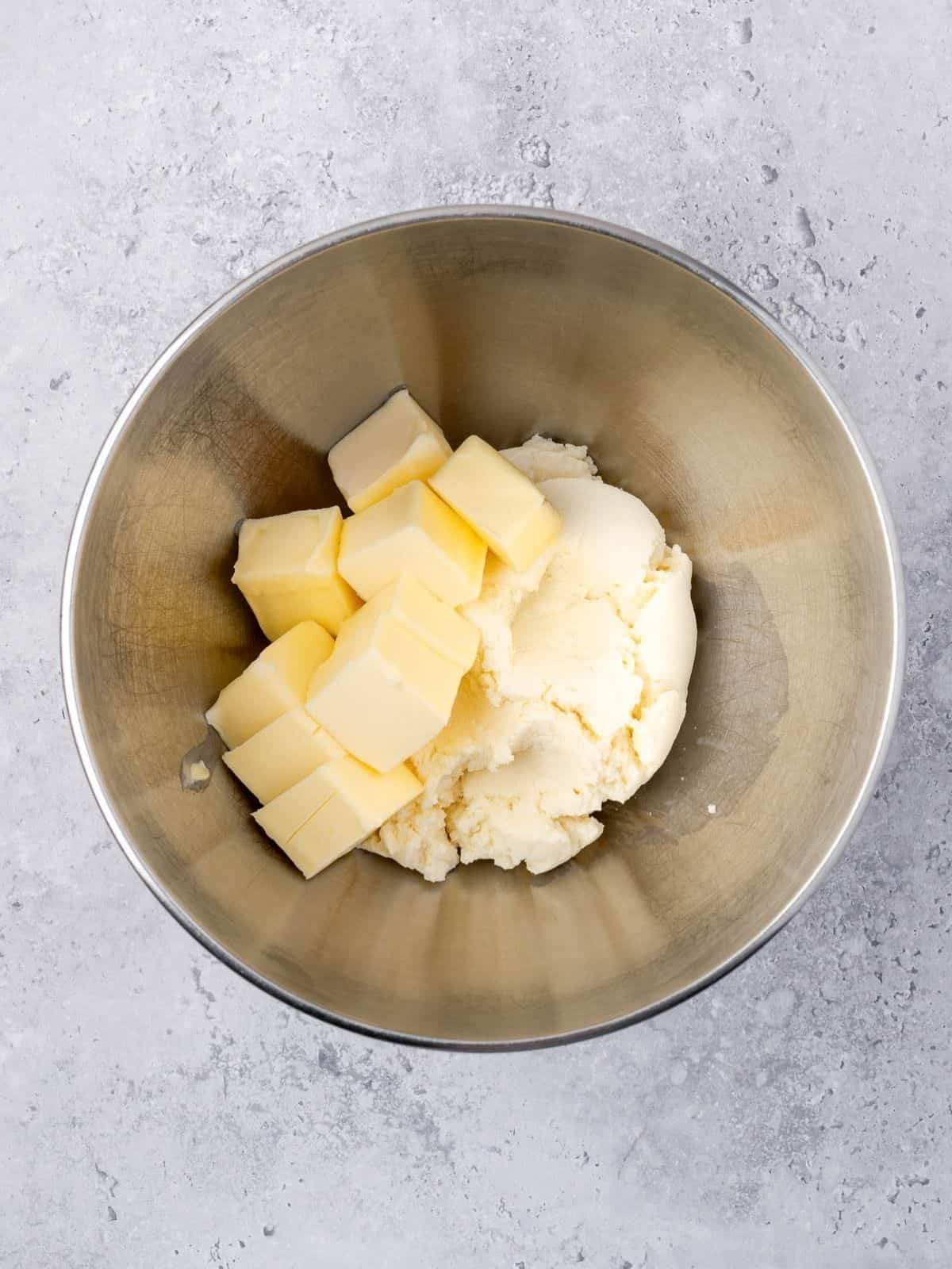 Butter and ricotta in a bowl of a stand mixer.
