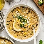 A bowl of Mediterranean white chicken chili, garnished with jalapeños, feta, and a lemon wedge.