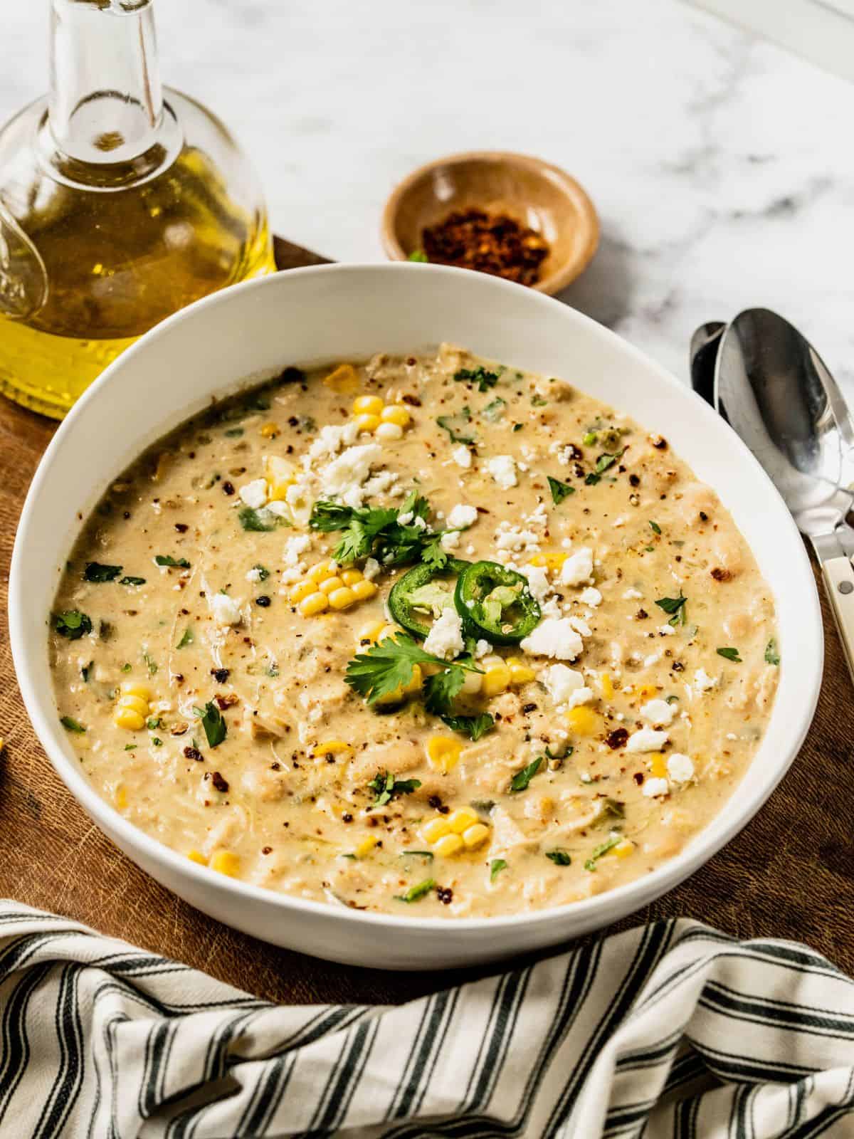 A bowl of Mediterranean white chicken chili, garnished with jalapeños, feta, and a lemon wedge.