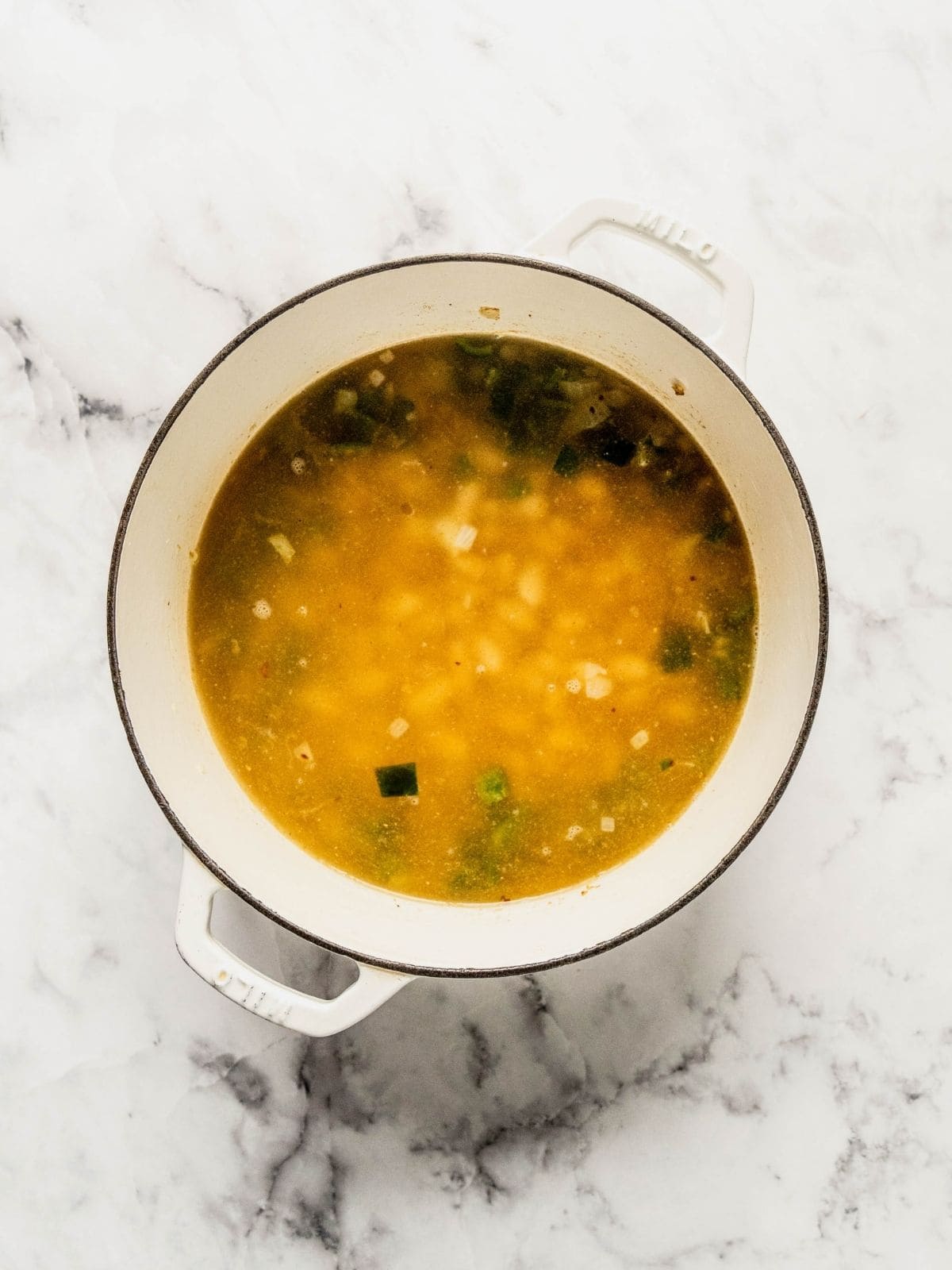 Soup pot with broth, beans and corn added to the fried aromatics.