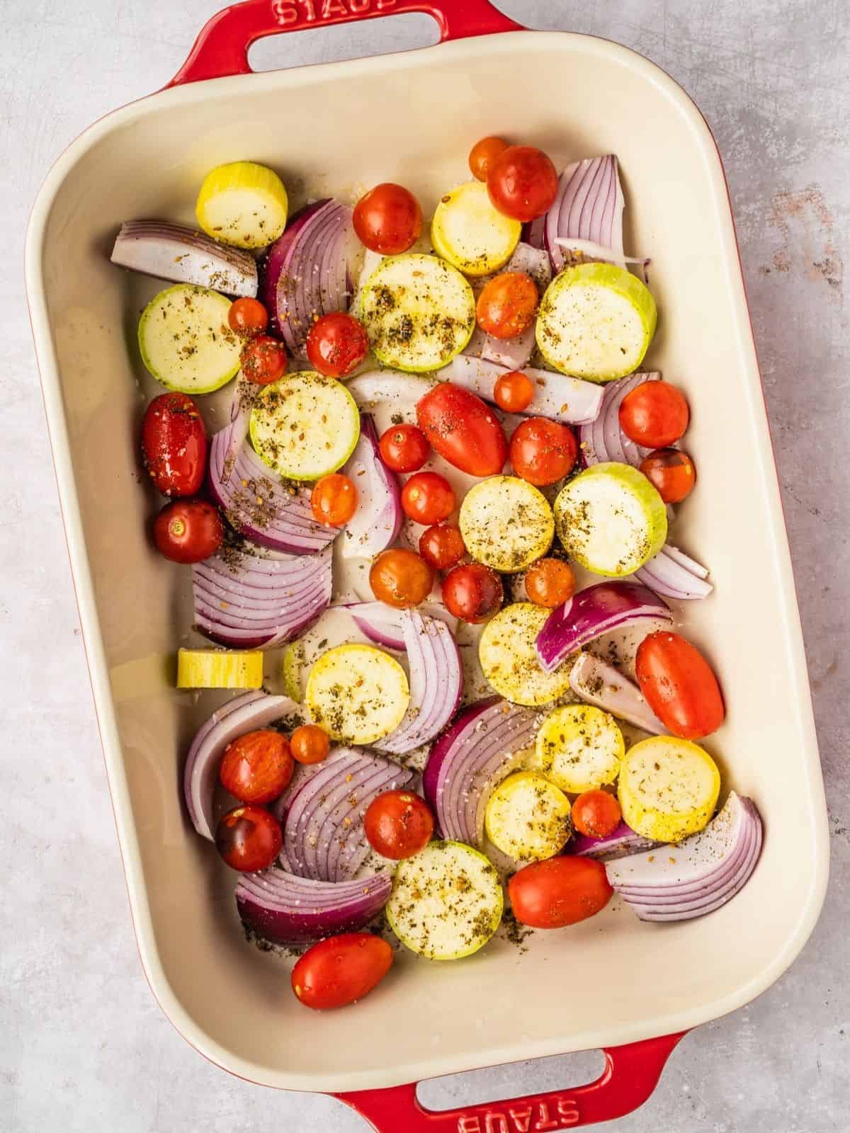 Baking dish with cherry tomatoes, sliced summer squash, red onion wedges dressed in oil and za'atar.