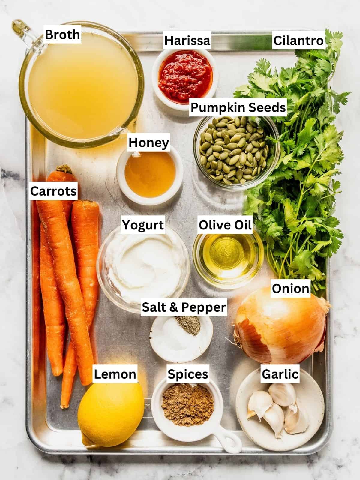 Carrot soup with harissa and yogurt recipe ingredients with individual labels on a metal tray.