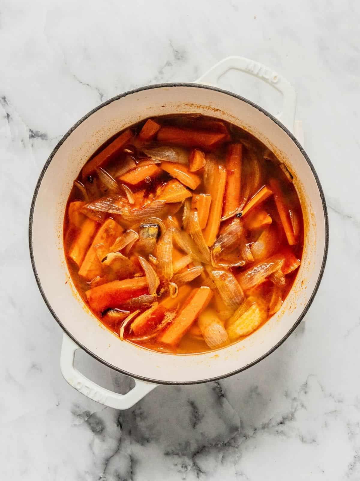 Soup pot with roasted carrots, onions, broth and other aromatics.
