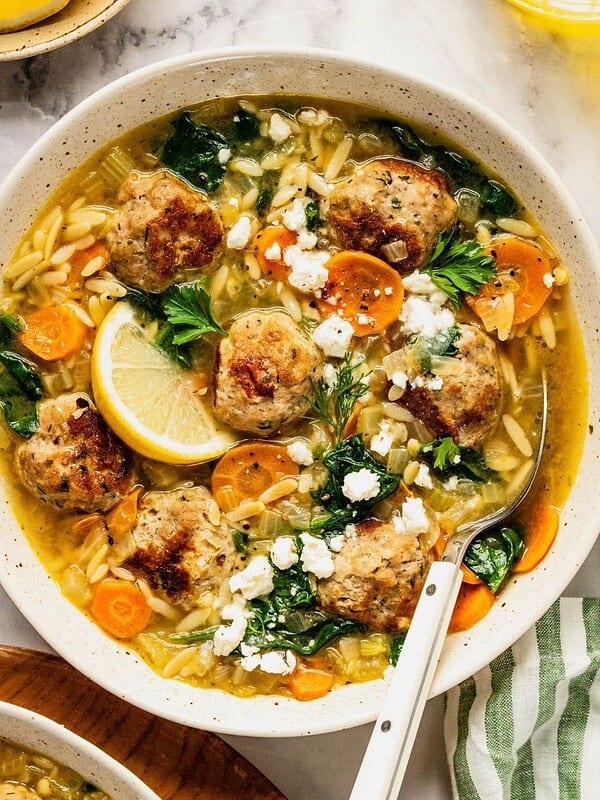 Turkey meatball orzo soup in a bowl garnished with fresh dill and parsley.
