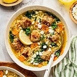Turkey meatball orzo soup in a bowl garnished with fresh dill and parsley.