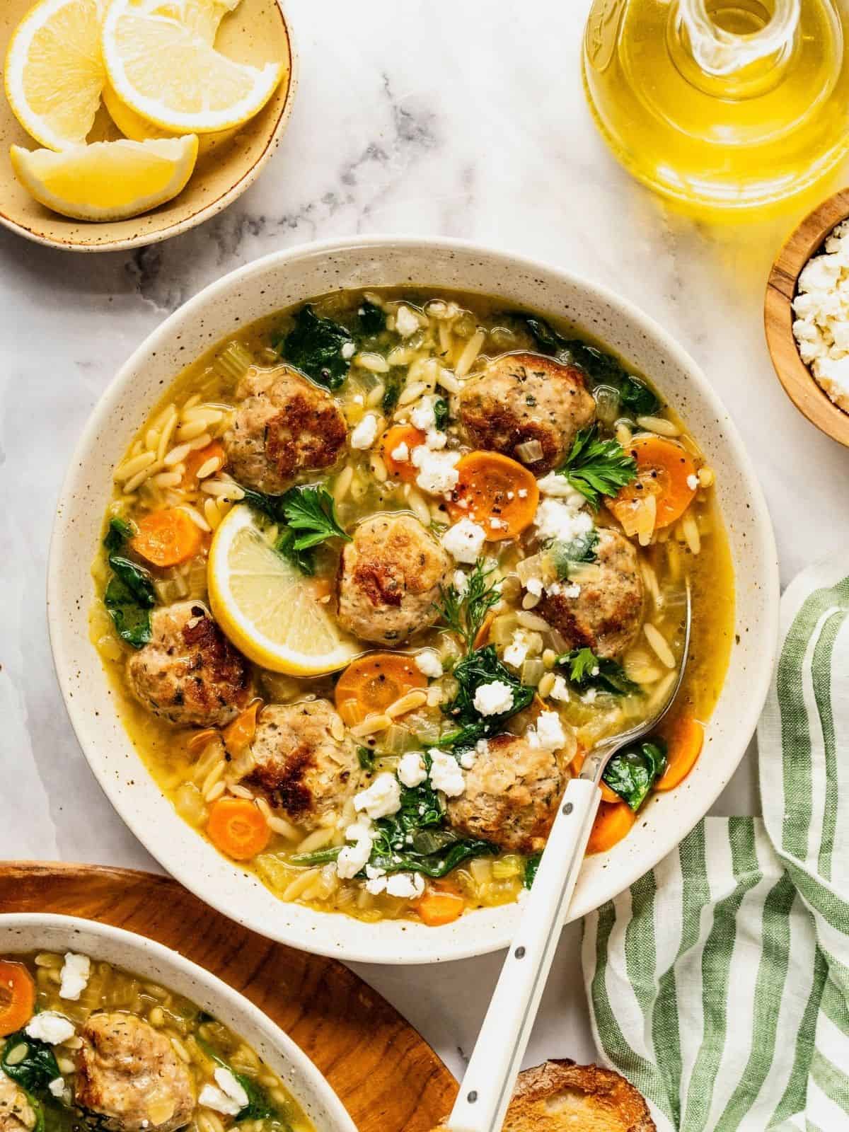 Turkey meatball orzo soup in a bowl garnished with fresh dill and parsley.