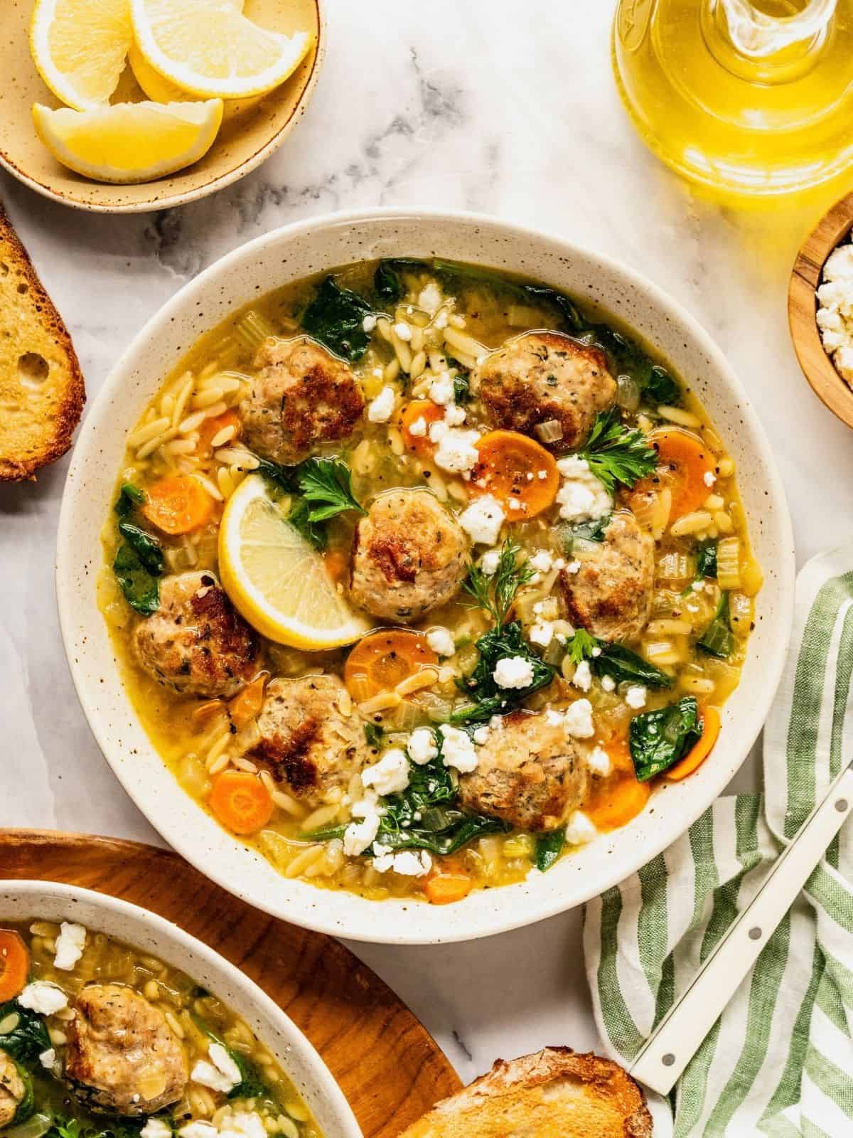 Turkey meatball orzo soup in a bowl garnished with fresh dill and parsley.