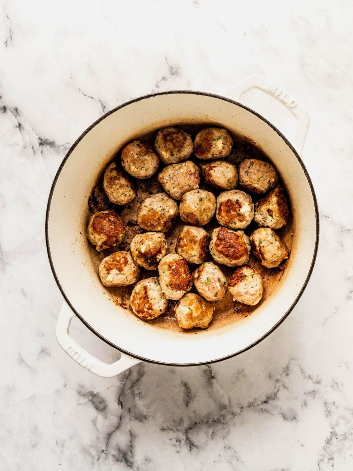 Turkey meatballs browning in a soup pot.