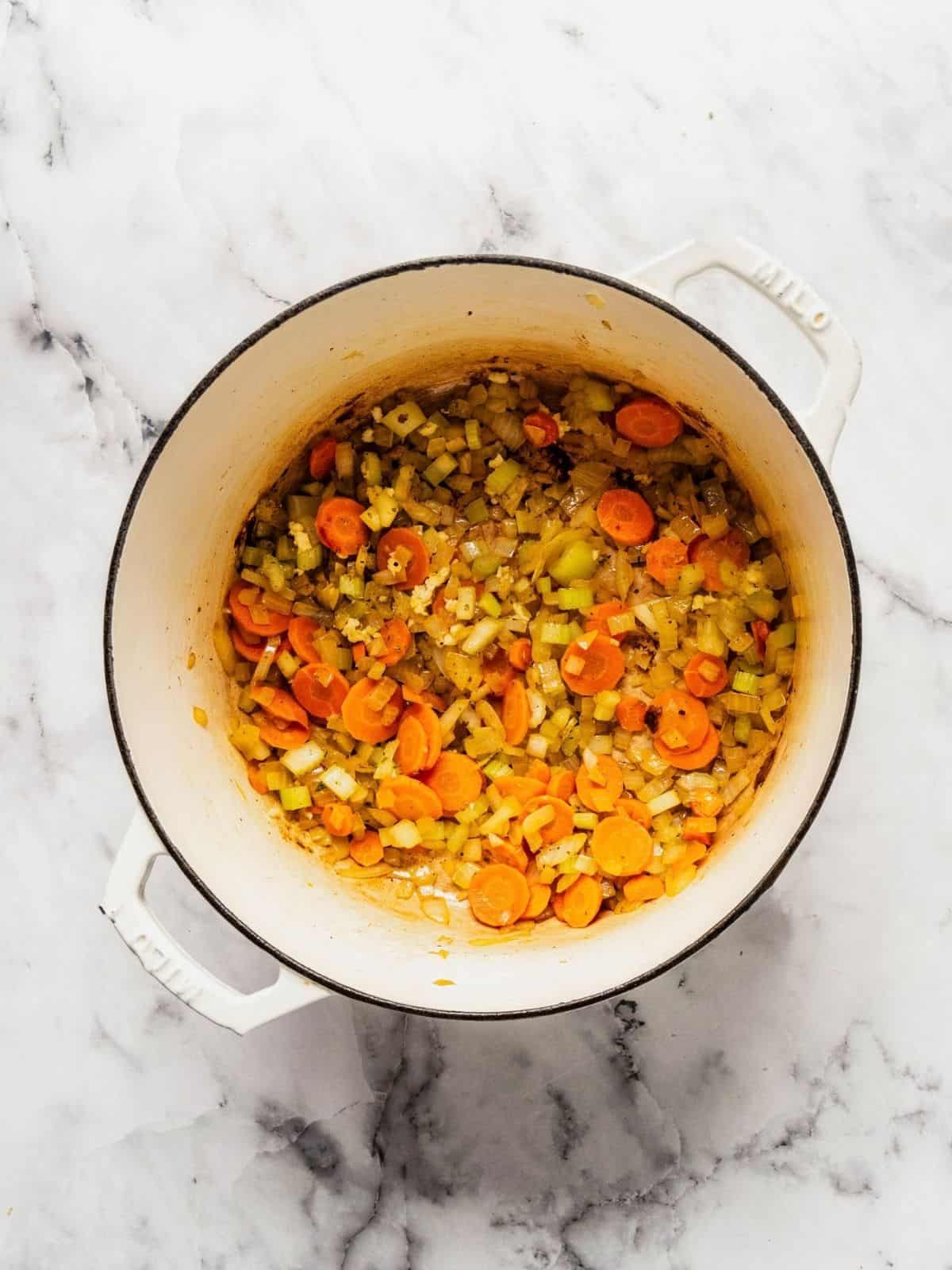 Soup pot with carrots, celery and onion frying in olive oil.
