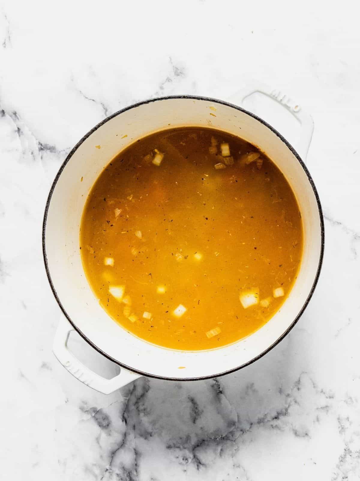 Adding the broth to the soup pot.