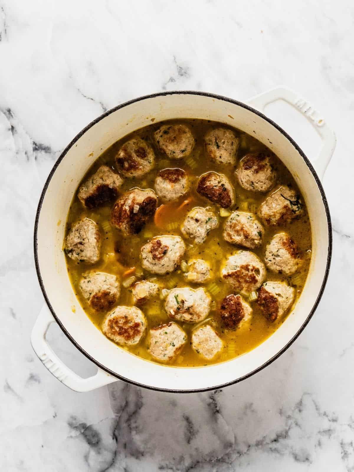 Recipe step showing the addition of the seared turkey meatballs to the soup pot.
