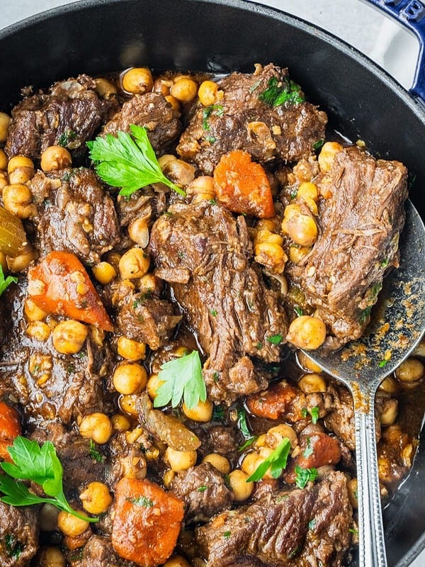 Beef chickpea stew in a pot with carrots, celery and parsley.