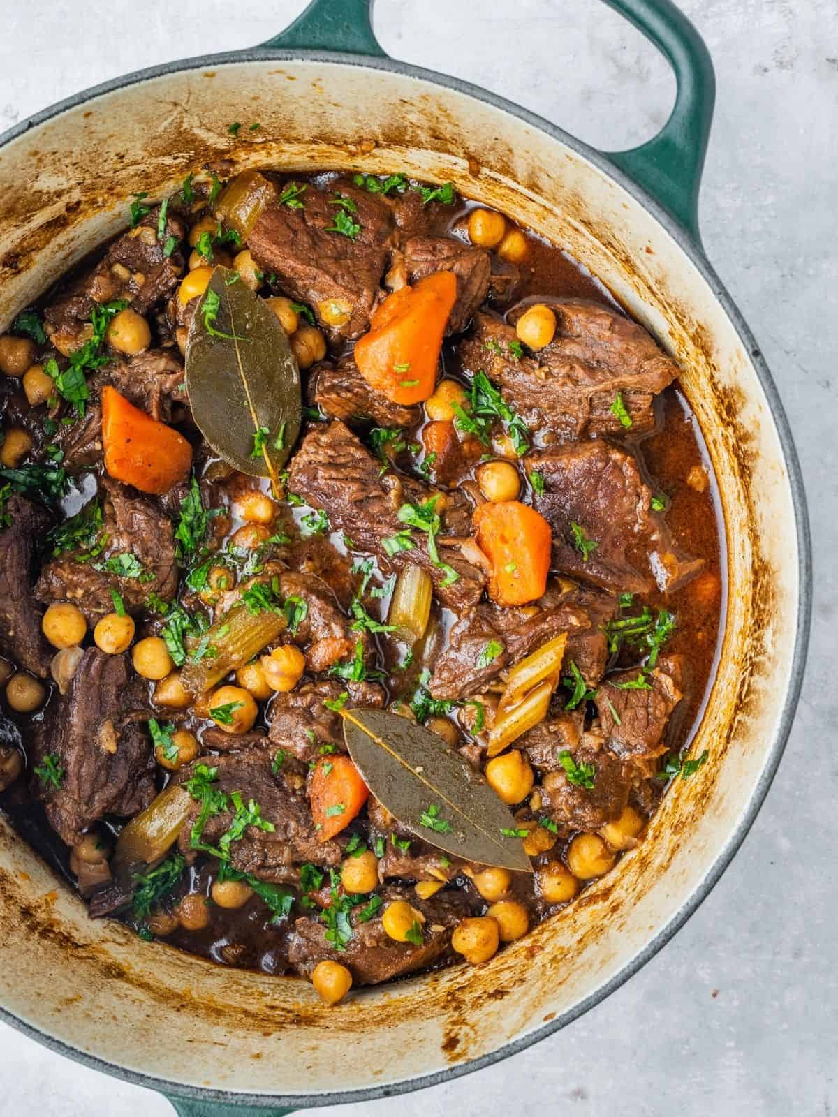 Beef chickpea stew in a pot with carrots, celery and parsley.