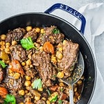 Beef chickpea stew in a pot with carrots, celery and parsley.