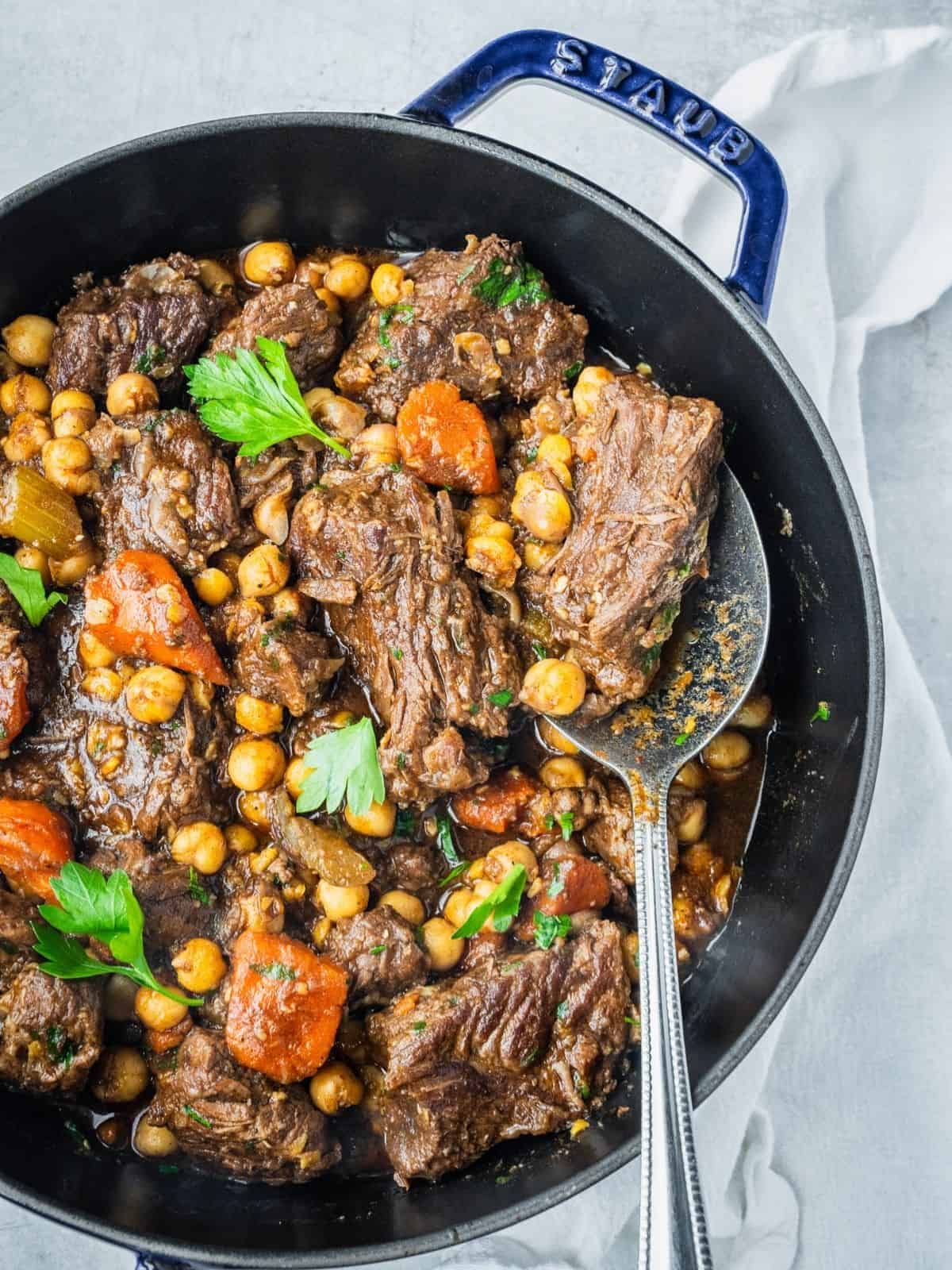 Beef chickpea stew in a pot with carrots, celery and parsley.