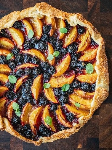 Peach blueberry galette on a wooden board.