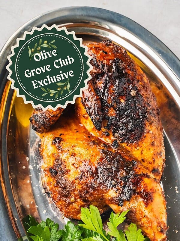 Portuguese Shop Style grilled Piri Piri Chicken half on a platter with parsley and lemon.